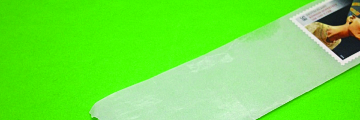 Ein Silikinträgerpapier mit selbstklebender Briefmarke vor grünem Hintergrund